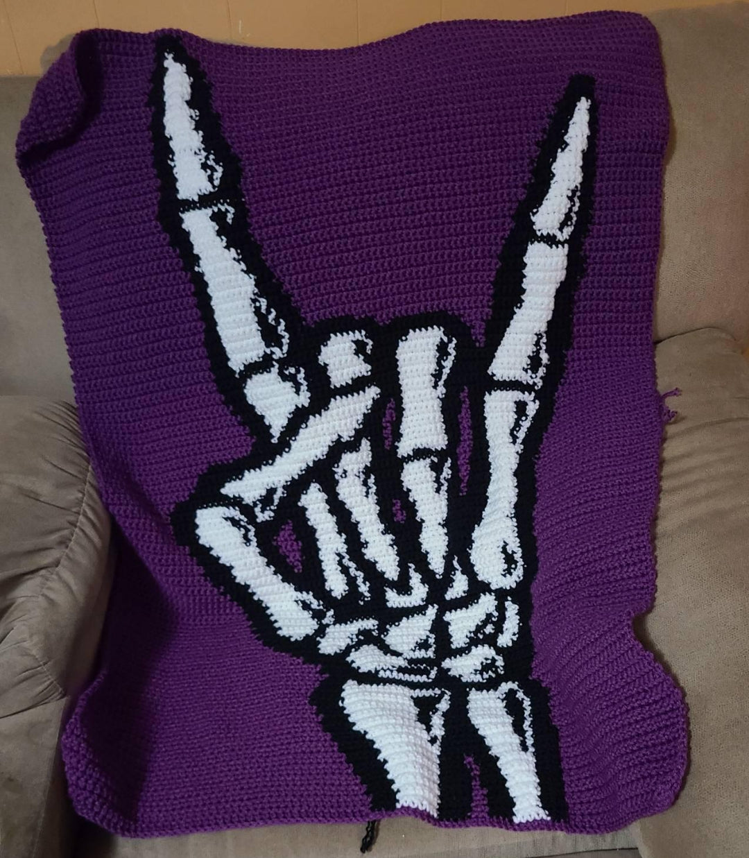 Skeleton Hand “Rock On” SC Crochet Pattern is a bold gothic Halloween graphgan featuring a skeletal hand making the classic rock-on gesture. With its purple, black and white color palette, this design is perfect for Halloween decor, music lovers, rock and punk fans, and anyone who loves edgy crochet projects.