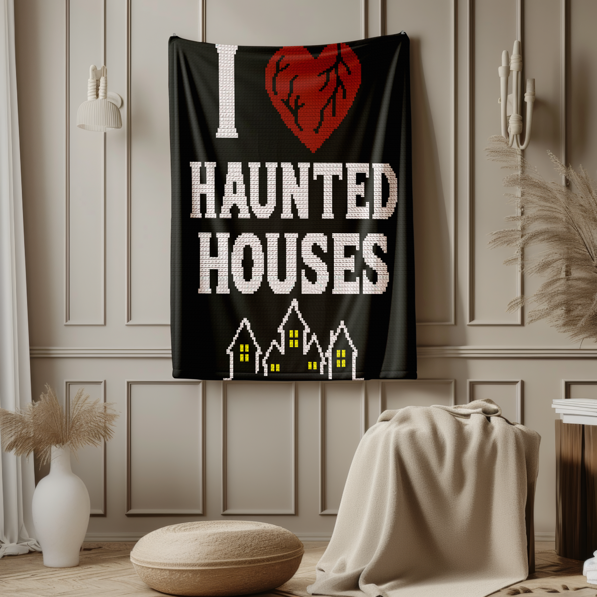 I Heart Haunted Houses SC crochet blanket hanging on a wall with bold haunted house lettering and glowing yellow windows.