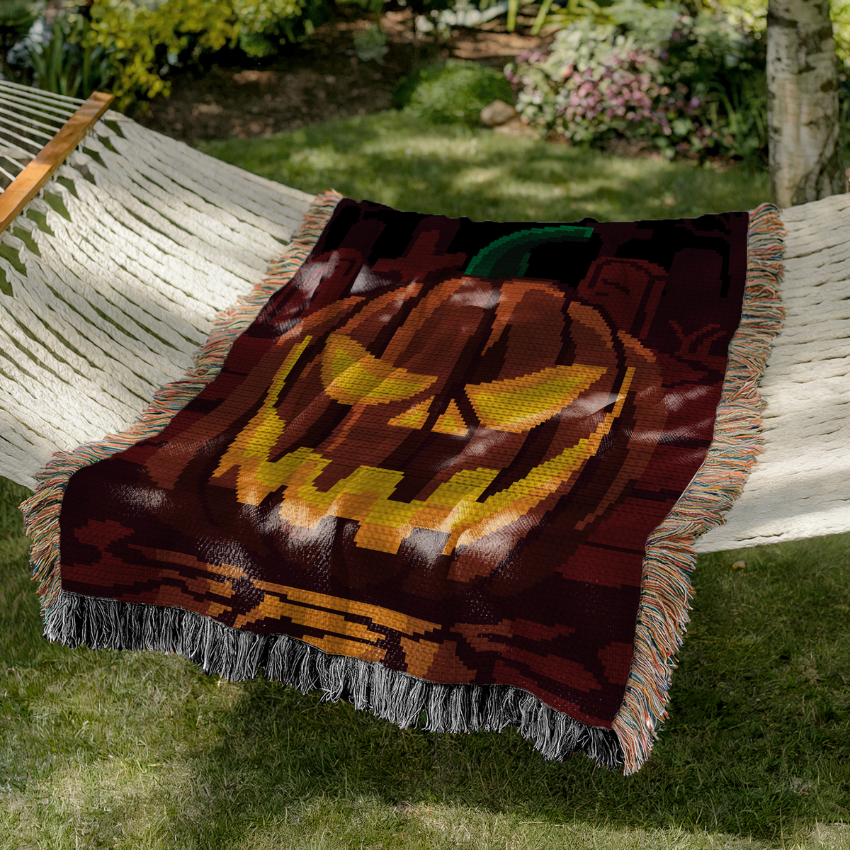 Pumpkin on a Graveyard crochet blanket displayed on a hammock in a garden setting.