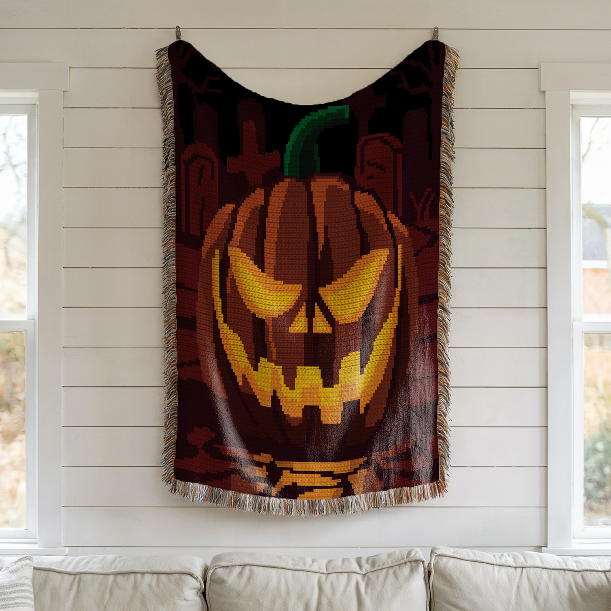 Pumpkin on a Graveyard crochet blanket wall display with glowing jack-o-lantern and graveyard background.