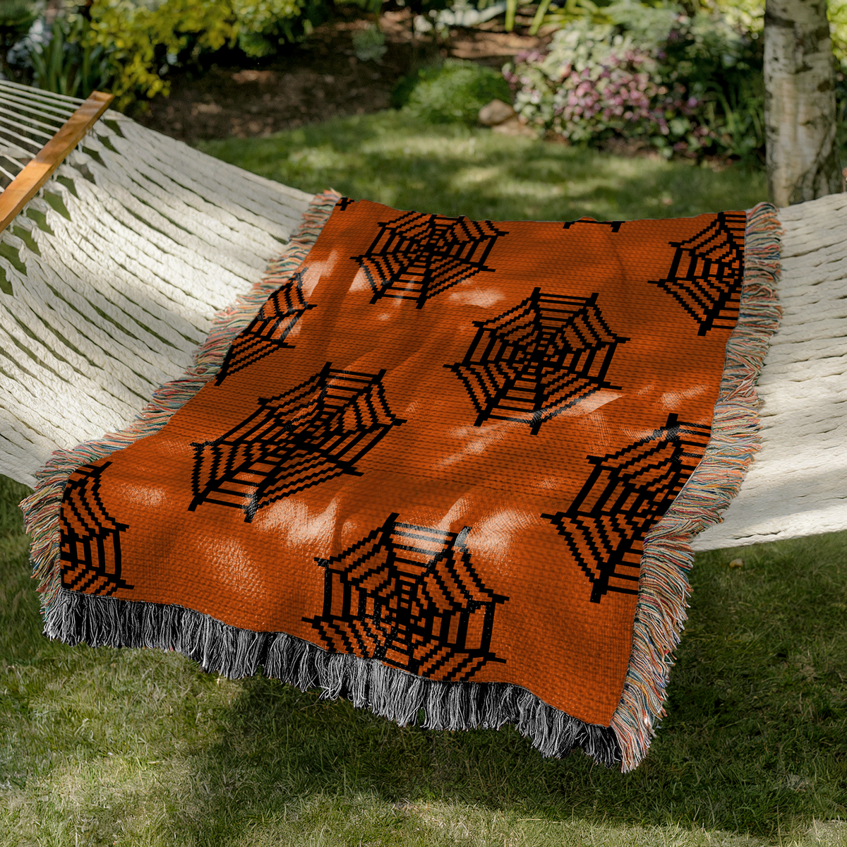 Orange and black spider web crochet blanket styled outdoors on a hammock
